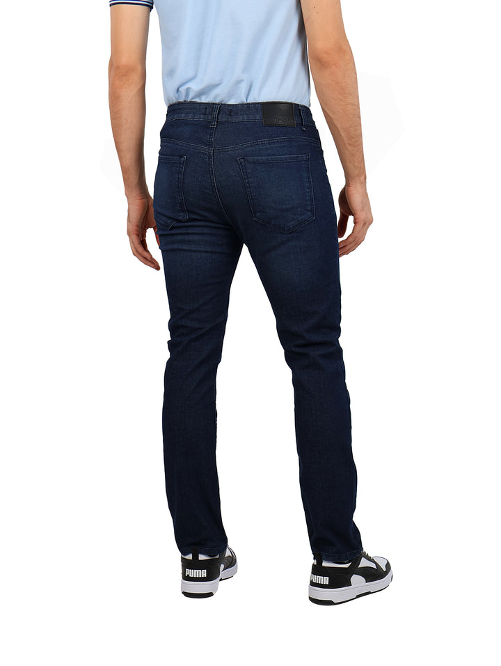 Hombre vistiendo pantalones jeans rectos de color azul oscuro, camiseta azul claro y tenis blancos con negro.