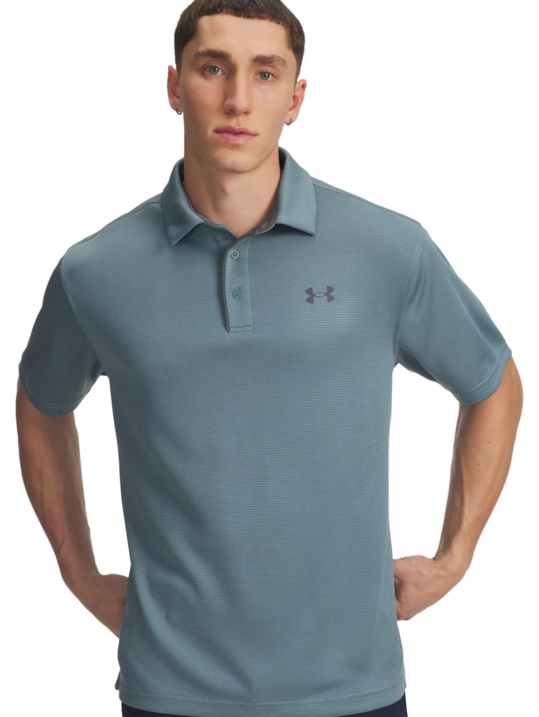 Hombre vistiendo una playera polo deportiva de color azul con logo de Under Armour en el pecho.