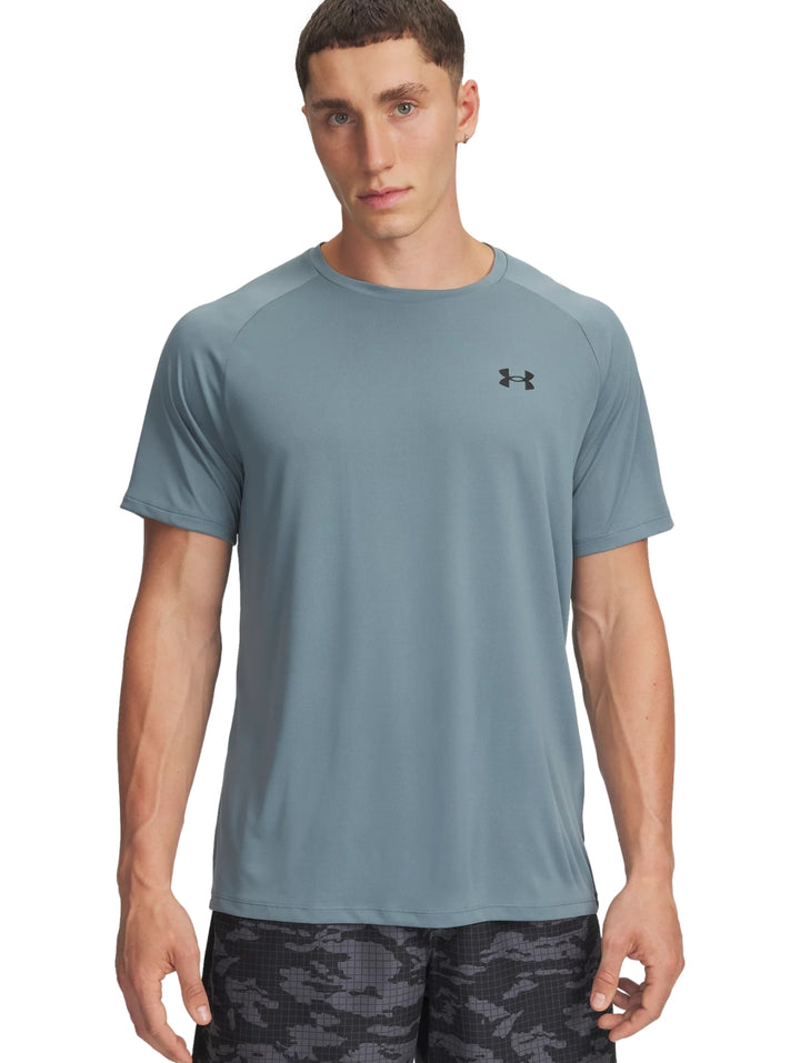 Hombre vistiendo una camiseta deportiva de manga corta color azul grisáceo de la marca Under Armour.
