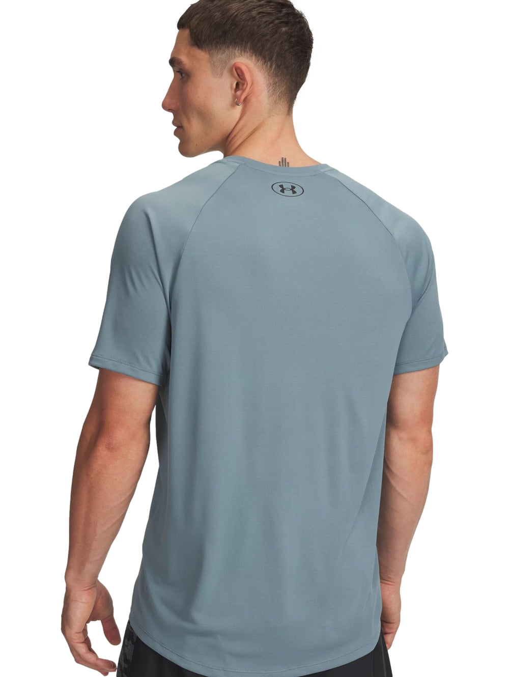Hombre vistiendo una camiseta deportiva de manga corta color azul grisáceo de la marca Under Armour.