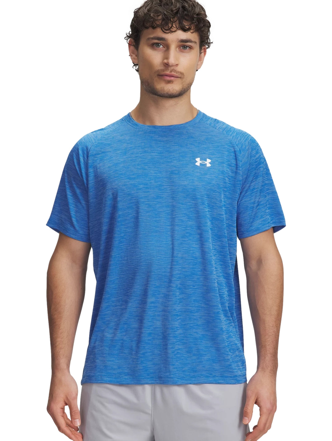 Hombre vistiendo una camiseta deportiva azul de manga corta con logotipo de Under Armour en el pecho.