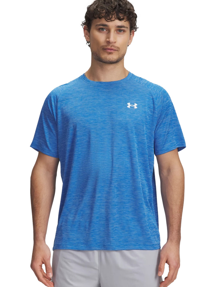 Hombre vistiendo una camiseta deportiva azul de manga corta con logotipo de Under Armour en el pecho.