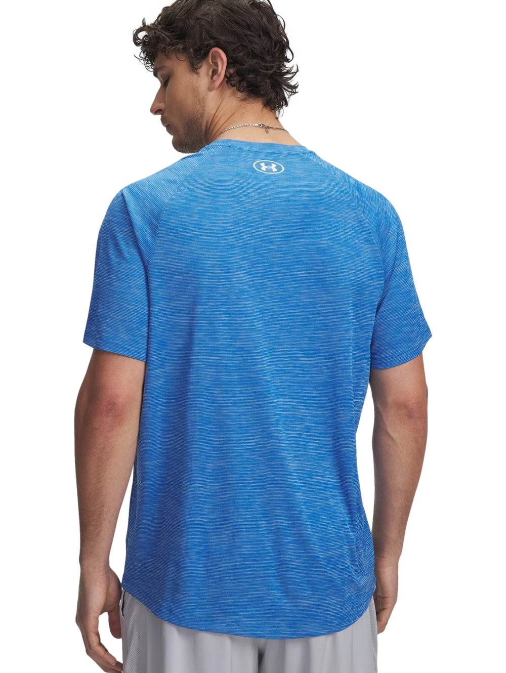 Hombre vistiendo una camiseta deportiva azul de manga corta con logotipo de Under Armour en el pecho.