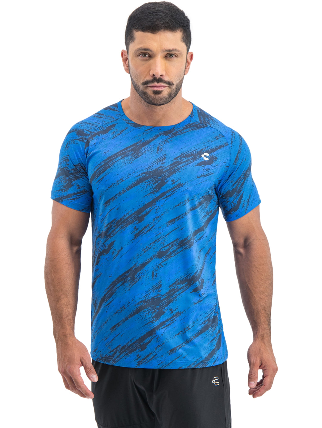 Playera deportiva azul de manga corta con estampado abstracto en tonos oscuros y logotipo blanco en el pecho.