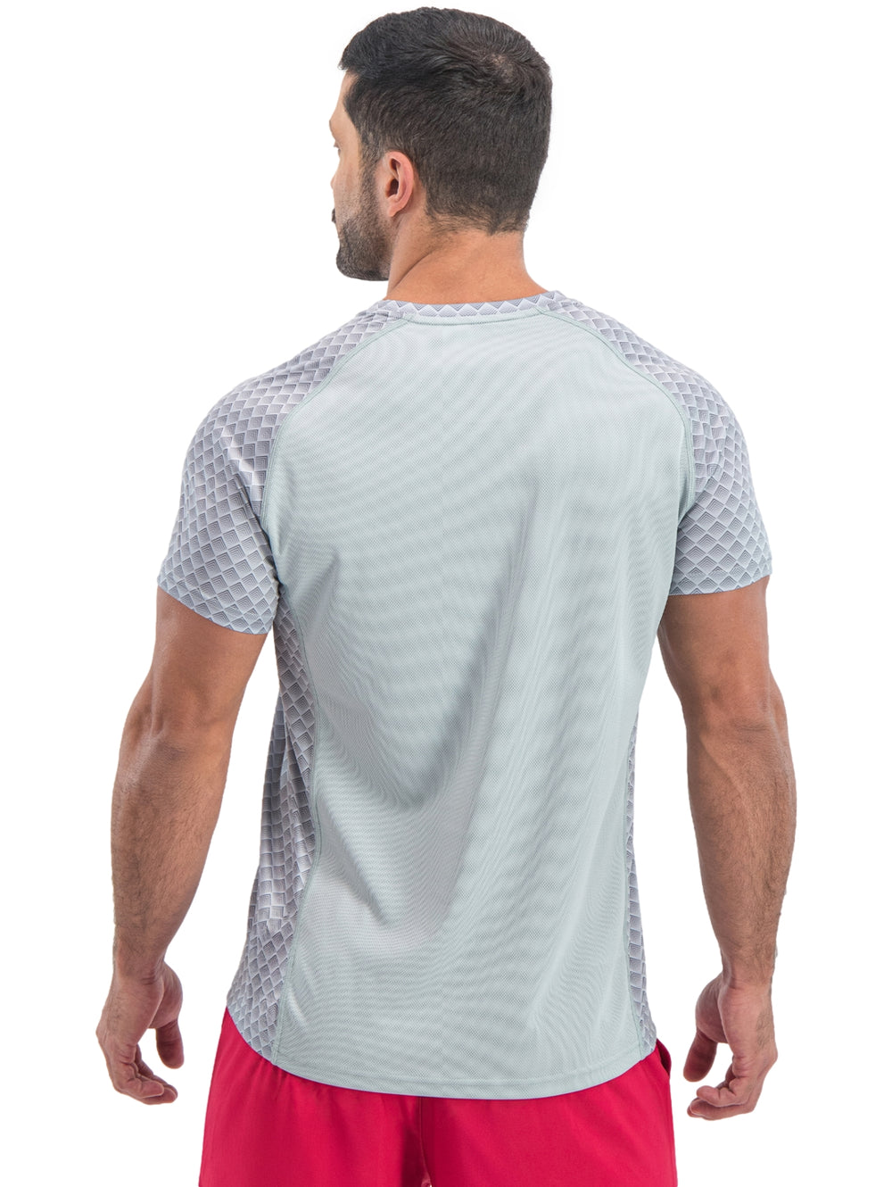 Hombre vistiendo playera deportiva de manga corta color gris claro con patrón geométrico.