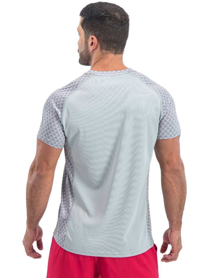 Hombre vistiendo playera deportiva de manga corta color gris claro con patrón geométrico.