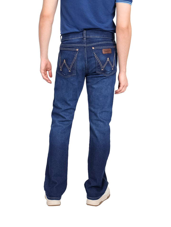 Hombre vistiendo jeans Wrangler color índigo estilo slim boot retro.