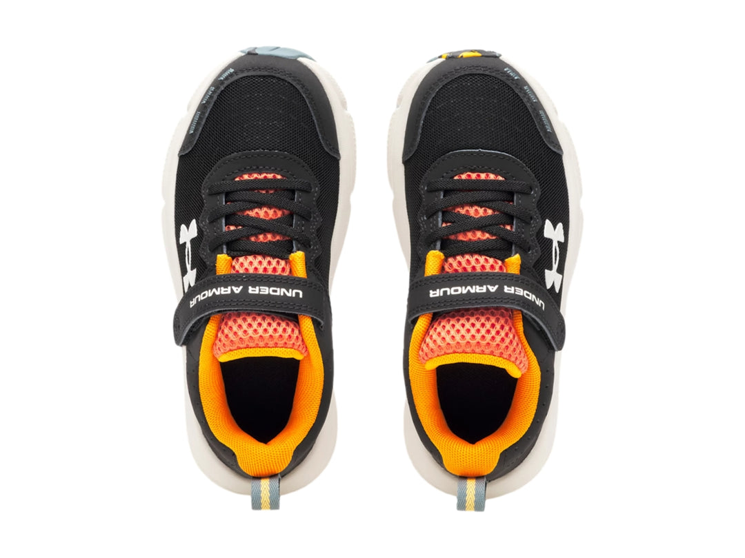 Tenis deportivos Under Armour para niño en color negro con detalles naranja y suela blanca.