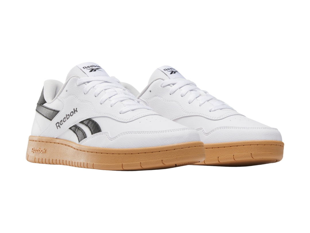 Tenis Reebok blancos con detalles en negro y suela de goma color café.