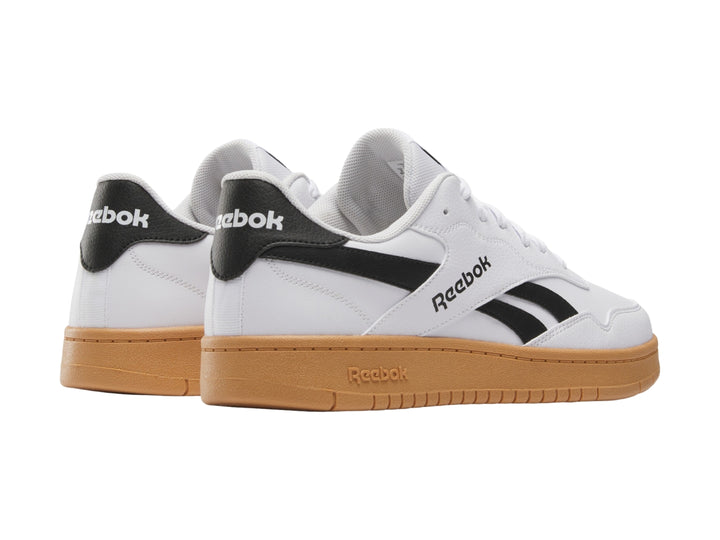 Tenis Reebok blancos con detalles en negro y suela de goma color café.