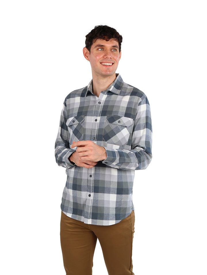 Hombre vistiendo camisa de franela a cuadros en colores gris y blanco con dos bolsillos frontales.