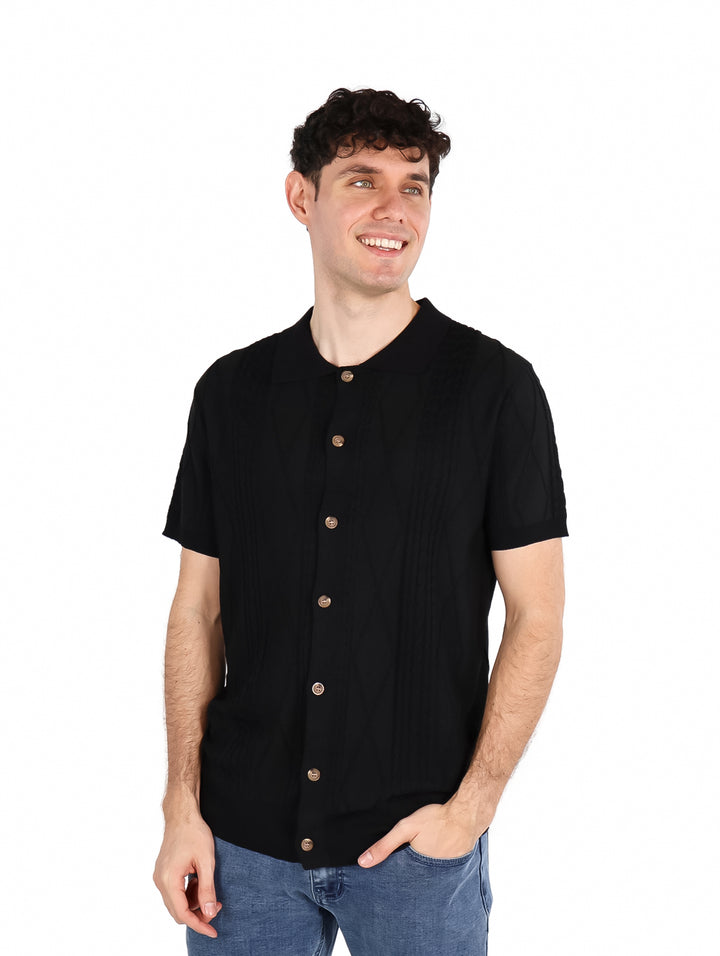 Hombre vistiendo una playera polo tejida de color negro con botones frontales y manga corta.