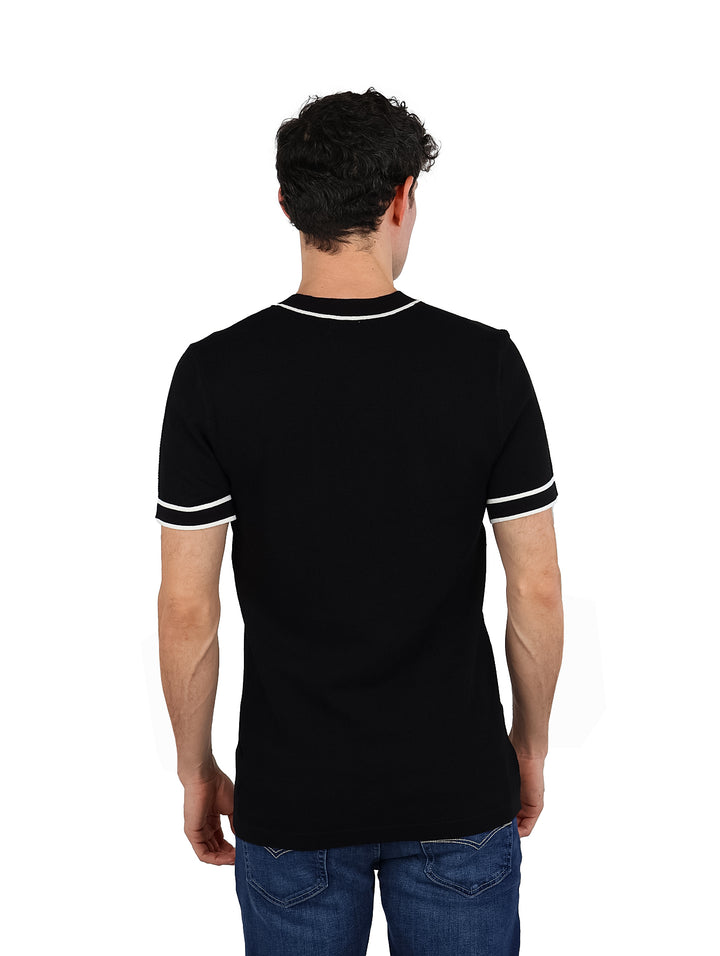 Hombre vistiendo playera tejida color negro con detalles blancos en el cuello y los bordes de las mangas.