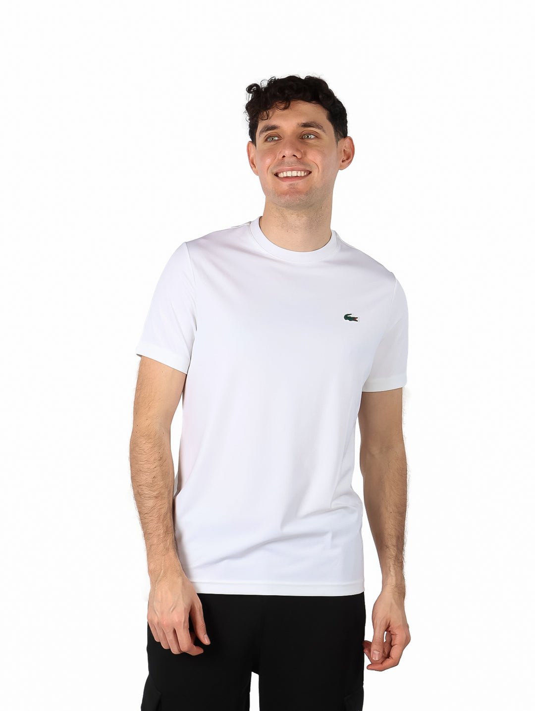 Hombre vistiendo una playera blanca de manga corta y cuello redondo de la marca Lacoste.