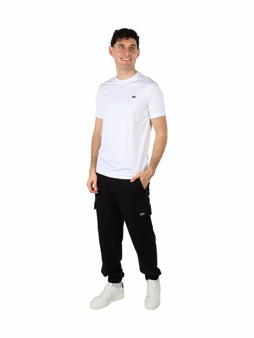 Hombre vistiendo una playera blanca de manga corta y cuello redondo de la marca Lacoste.