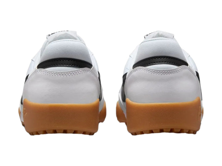 Tenis Nike blancos con logotipo negro y suela de goma color café claro.