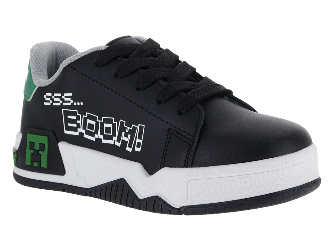 Tenis negros para niño con suela blanca y detalles decorativos en verde y blanco.