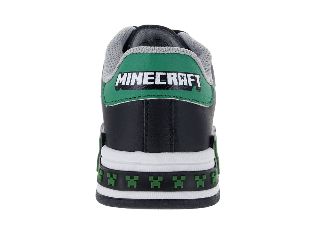 Tenis negros para niño con suela blanca y detalles decorativos en verde y blanco.