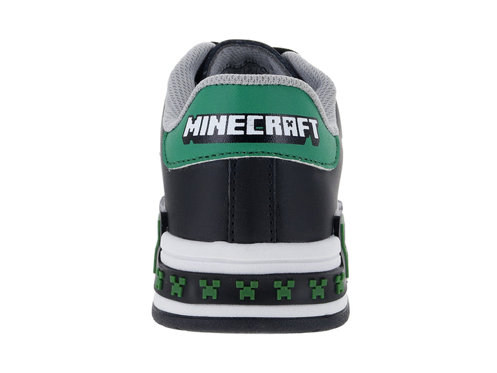 Tenis negros para niño con suela blanca y detalles decorativos en verde y blanco.