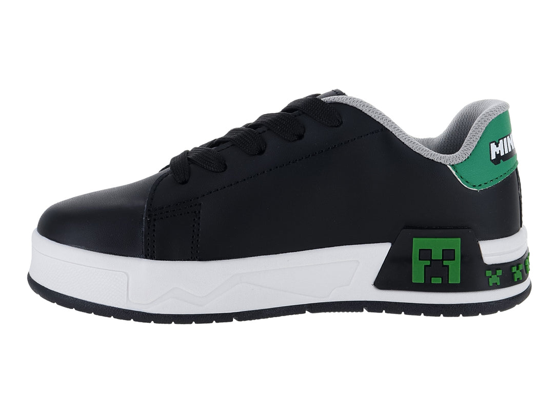 Tenis negros para niño con suela blanca y detalles decorativos en verde y blanco.