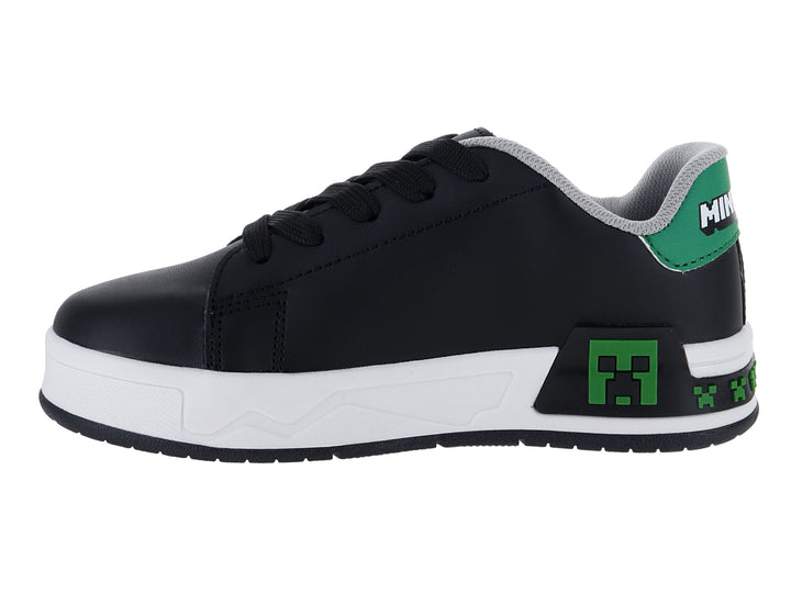 Tenis negros para niño con suela blanca y detalles decorativos en verde y blanco.