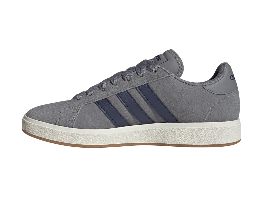 Tenis Adidas color gris con franjas azules y suela blanca.