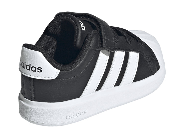 Tenis Adidas negros con tres franjas blancas, cierre de velcro y suela blanca.