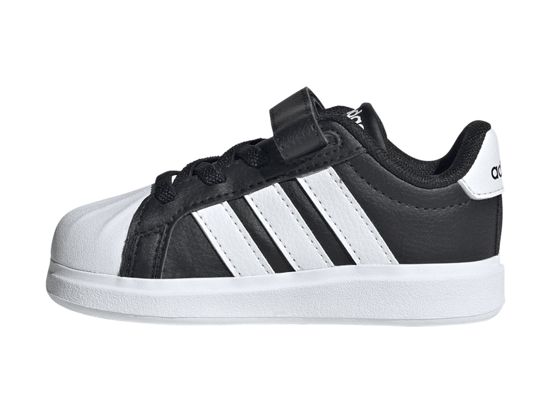 Tenis Adidas negros con tres franjas blancas, cierre de velcro y suela blanca.