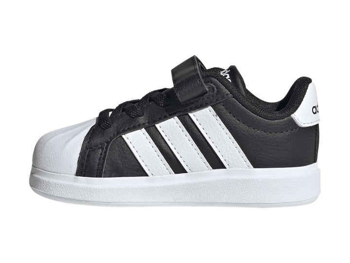 Tenis Adidas negros con tres franjas blancas, cierre de velcro y suela blanca.