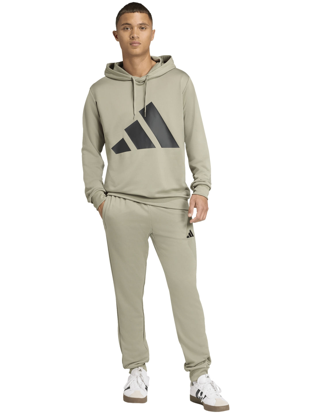 Hombre vistiendo conjunto deportivo Adidas color Silver Pebble compuesto por sudadera con capucha y pantalón.