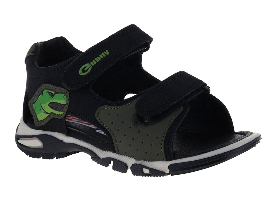 Sandalia infantil color negro con detalles verdes, dibujo de dinosaurio y suela blanca.