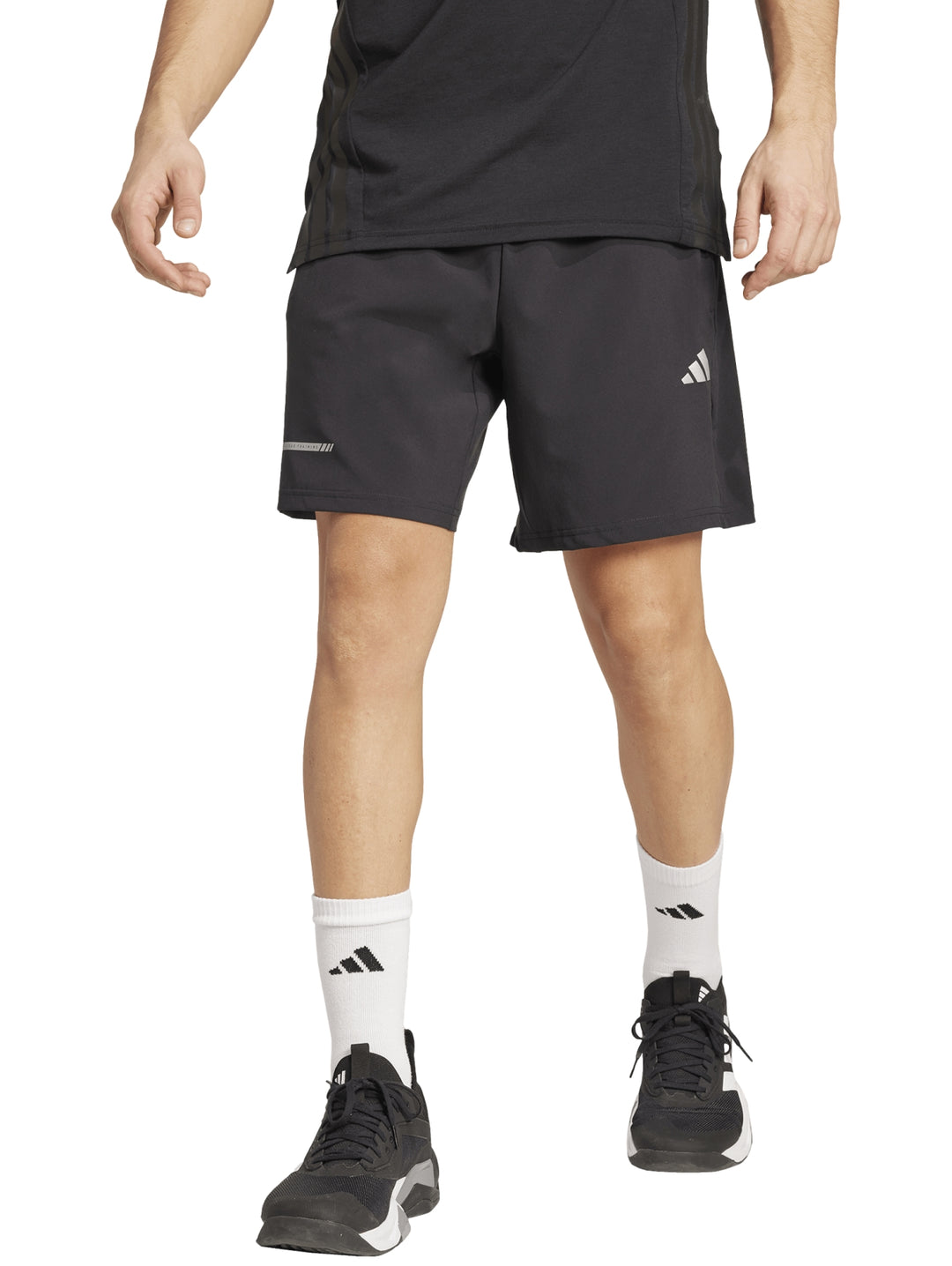 Hombre vistiendo shorts deportivos Adidas color negro con logo blanco en la pierna izquierda.