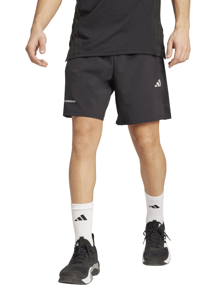 Hombre vistiendo shorts deportivos Adidas color negro con logo blanco en la pierna izquierda.