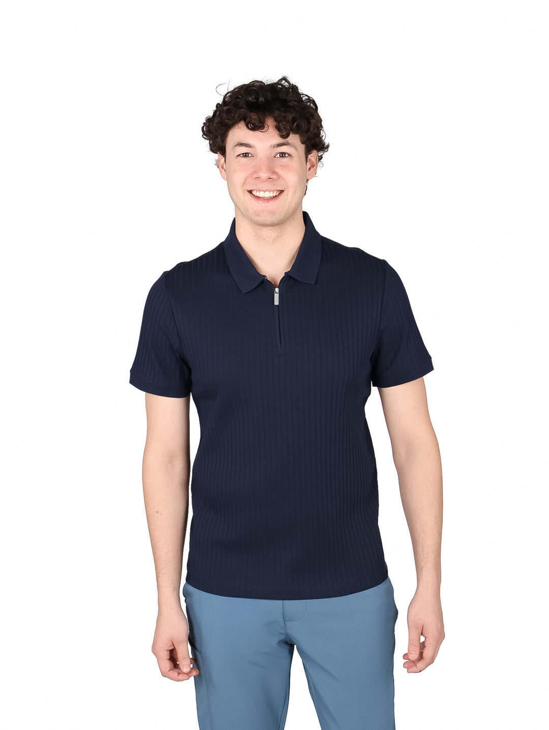 Hombre vistiendo una playera polo azul marino con cuello de cierre y textura acanalada.