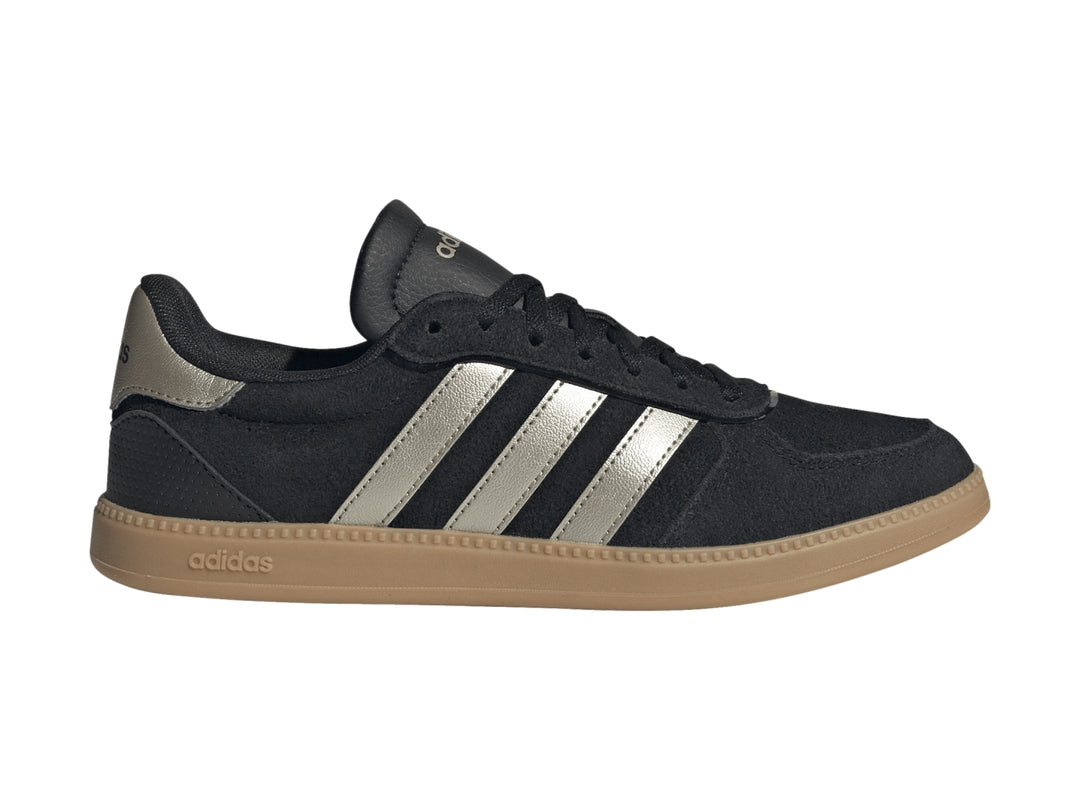 Tenis Adidas negros con tres franjas plateadas metálicas y suela de goma color caramelo.