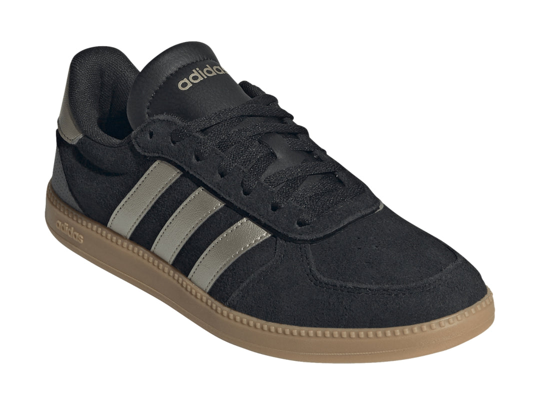Tenis Adidas negros con tres franjas plateadas metálicas y suela de goma color caramelo.
