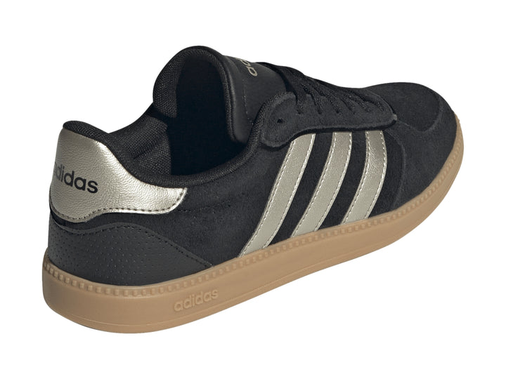 Tenis Adidas negros con tres franjas plateadas metálicas y suela de goma color caramelo.