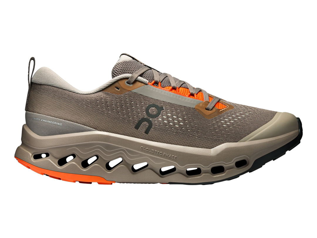Tenis deportivos On Cloudsurfer Trail 2 color gris topo con detalles naranjas y suela con tecnología CloudTec.
