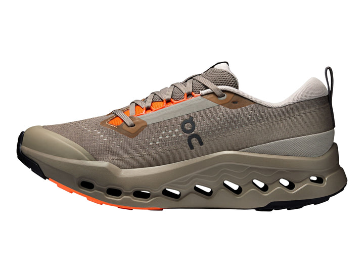 Tenis deportivos On Cloudsurfer Trail 2 color gris topo con detalles naranjas y suela con tecnología CloudTec.