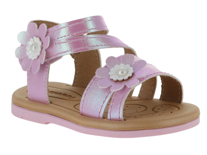 Sandalias rosas metálicas para niña con adornos de flores blancas y suela marrón.