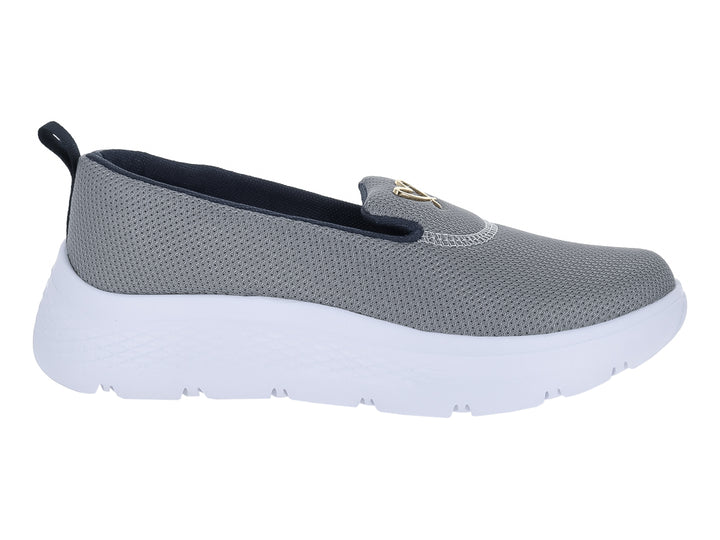 Zapato deportivo slip-on de color gris con suela blanca gruesa y detalle dorado en la parte superior.