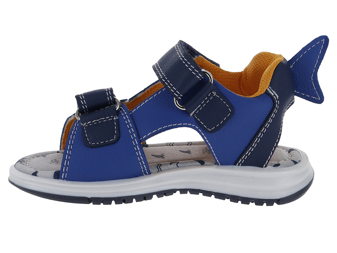 Sandalia infantil azul con diseño de tiburón, suela blanca y cierres de velcro.