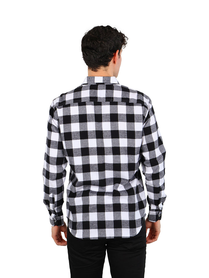 Hombre vistiendo camisa de franela a cuadros en color negro y blanco con pantalones negros.