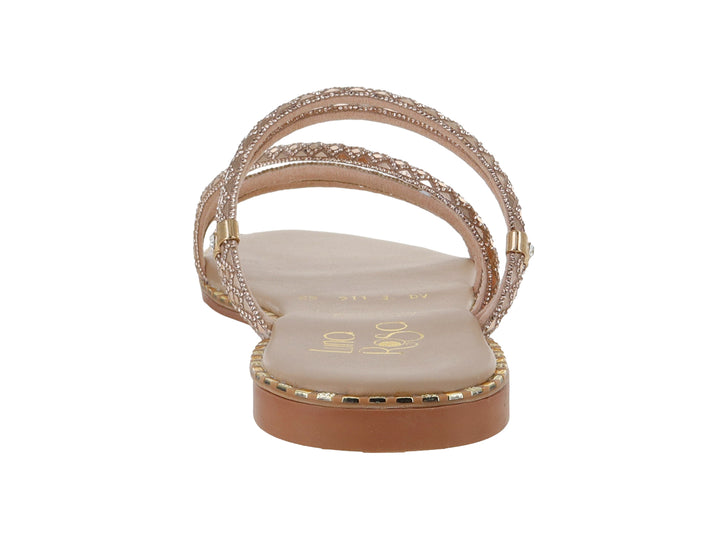 Sandalia plana para niña en color oro rosado con correas brillantes y suela delgada.