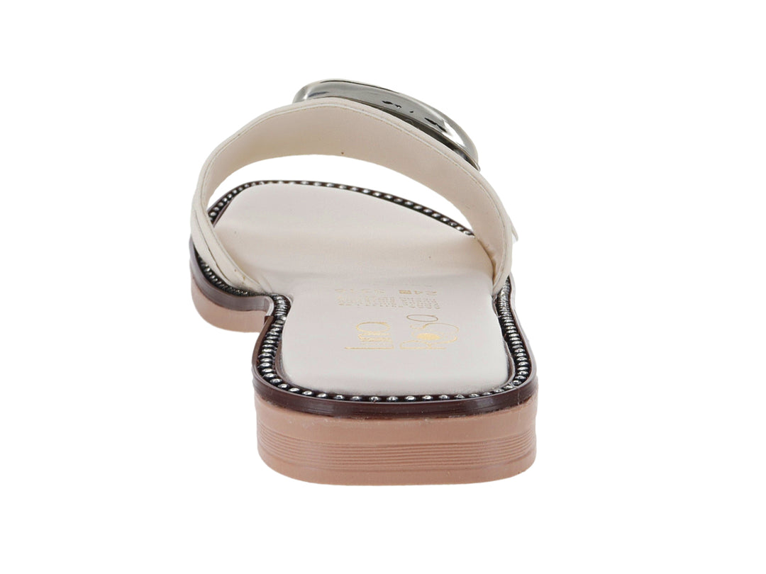 Sandalia plana color latte con una gran hebilla dorada decorativa en la parte superior.