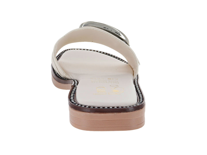 Sandalia plana color latte con una gran hebilla dorada decorativa en la parte superior.