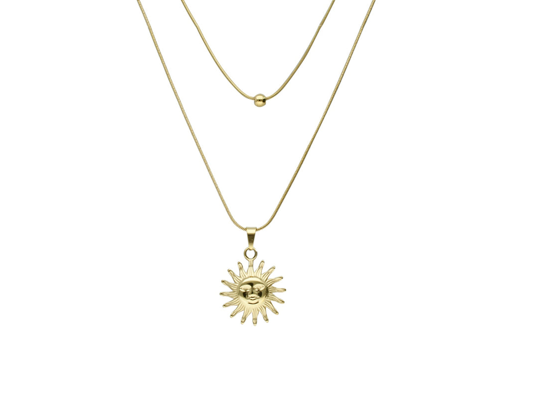 Collar dorado de doble cadena con un dije en forma de sol brillante sobre fondo blanco.