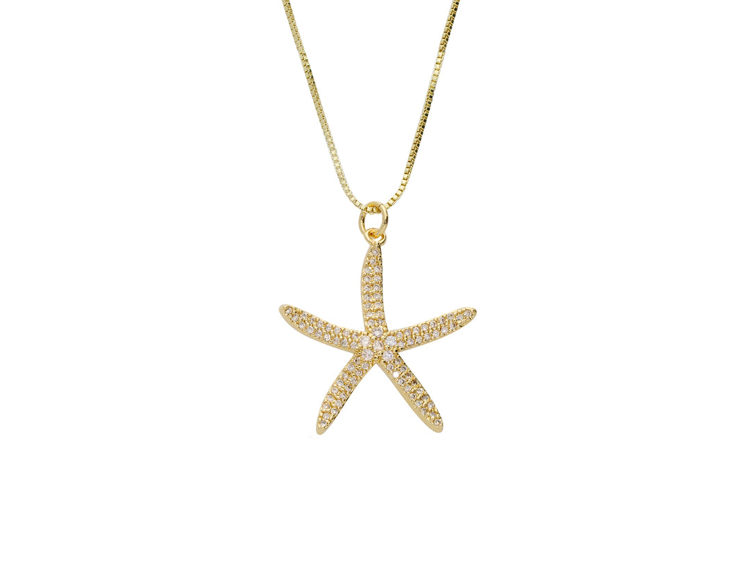 Collar dorado con dije en forma de estrella de mar adornada con brillantes sobre fondo blanco.