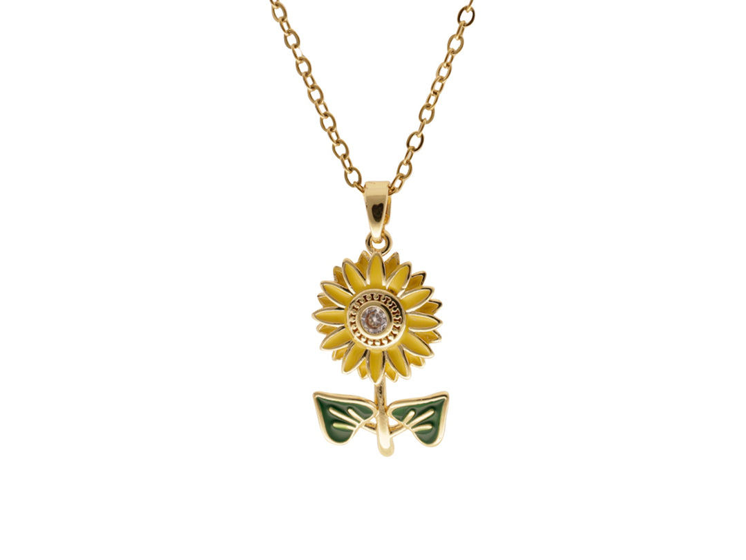 Collar dorado con dije en forma de girasol amarillo y hojas verdes sobre fondo blanco.