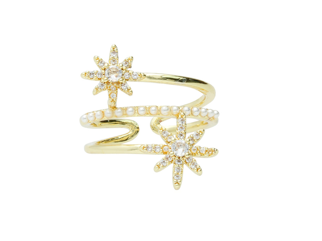 Anillo dorado en forma de espiral con dos estrellas brillantes y una hilera de perlas blancas.